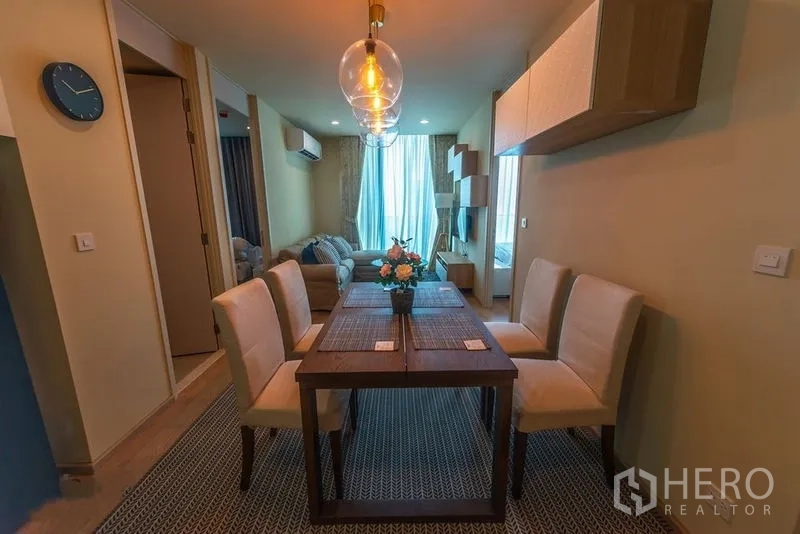 Condominium for rent in Watthana, Bangkok - Wooden dining table for four under glass pendant lighting in a contemporary space.