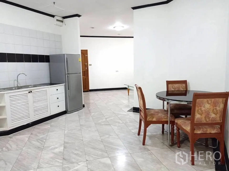 คอนโด for rent in Watthana, Bangkok - ครัวแบบเปิดตู้สีขาว อ่างล้างจานสแตนเลส ตู้เย็น และโต๊ะรับประทานอาหารทรงกลม