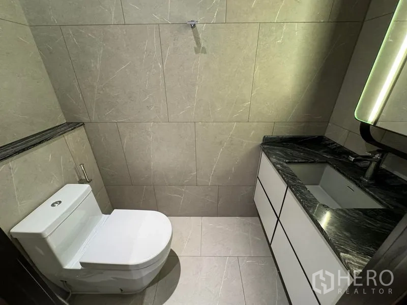 Condominium for rent in Watthana, Bangkok - Powder room with stone countertop vanity and toilet.