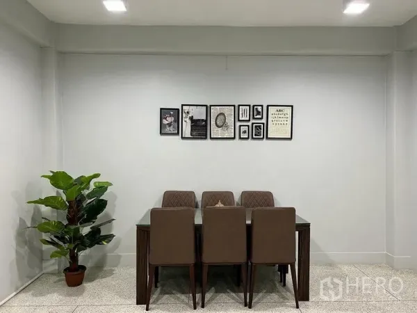 Shophouse for sale in Bang Kho Laem, Bangkok - Minimal dining area with six upholstered chairs, wall art and a potted plant.