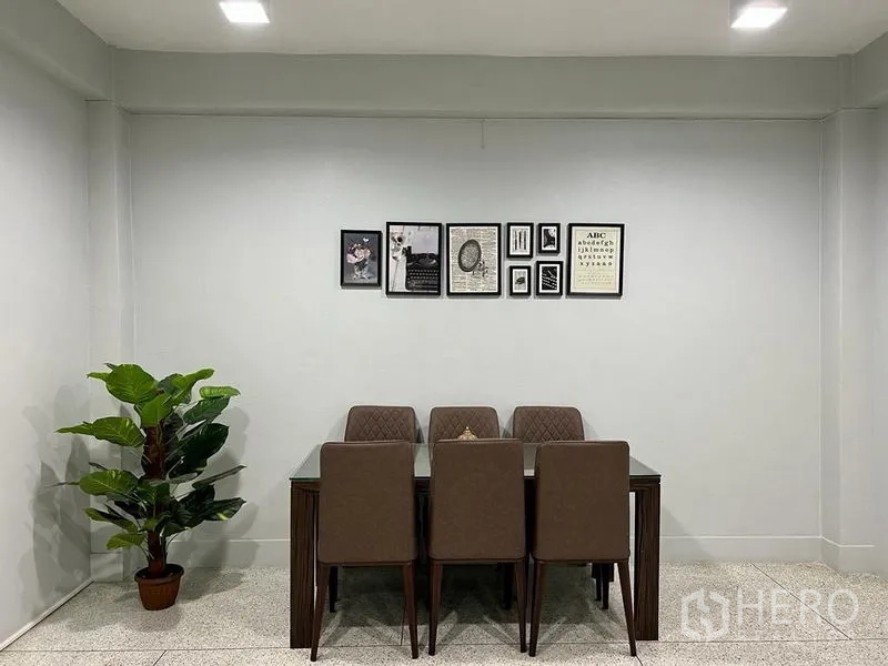 Shophouse for sale in Bang Kho Laem, Bangkok - Minimal dining area with six upholstered chairs, wall art and a potted plant.