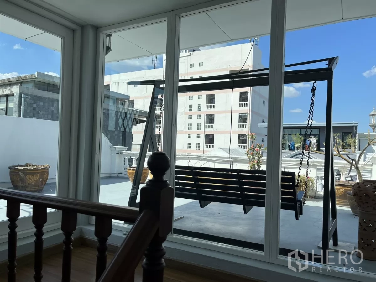 Home Office for rent - Glass‑enclosed landing overlooking rooftop swing bench and blue sky