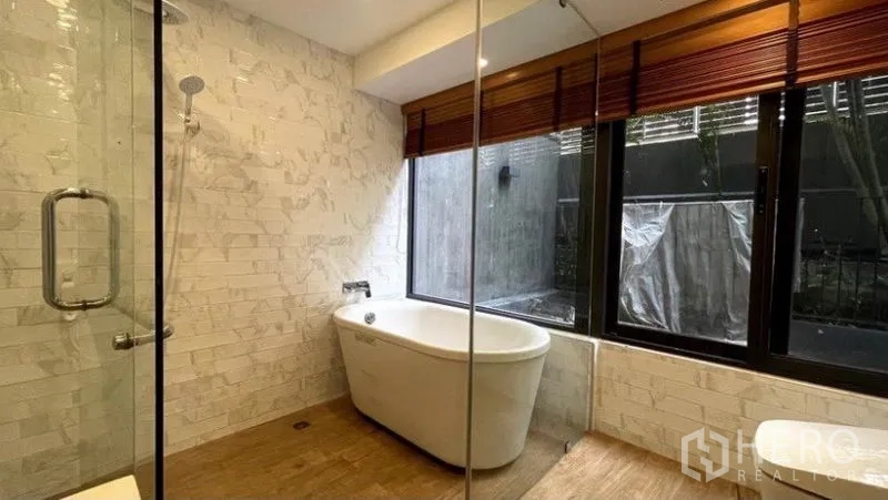 Condominium for rent in Watthana, Bangkok - Contemporary bathroom with freestanding bathtub beside the window and a glass-enclosed shower.