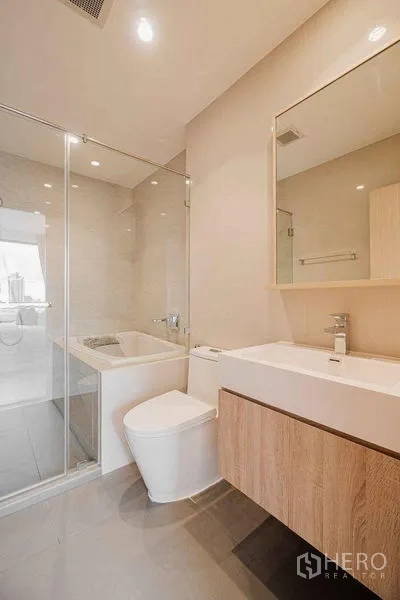 Condominium for rent in Watthana, Bangkok - Second bathroom featuring a bathtub, glass shower screen, and large mirror.