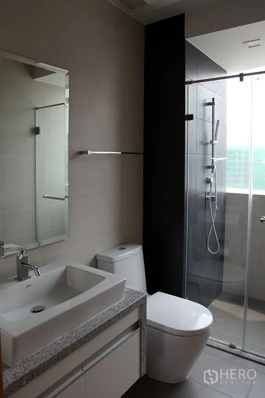 公寓 出租在Khlong Toei, Bangkok - 现代卫浴，方形台盆、石材台面、坐便器与玻璃淋浴间。