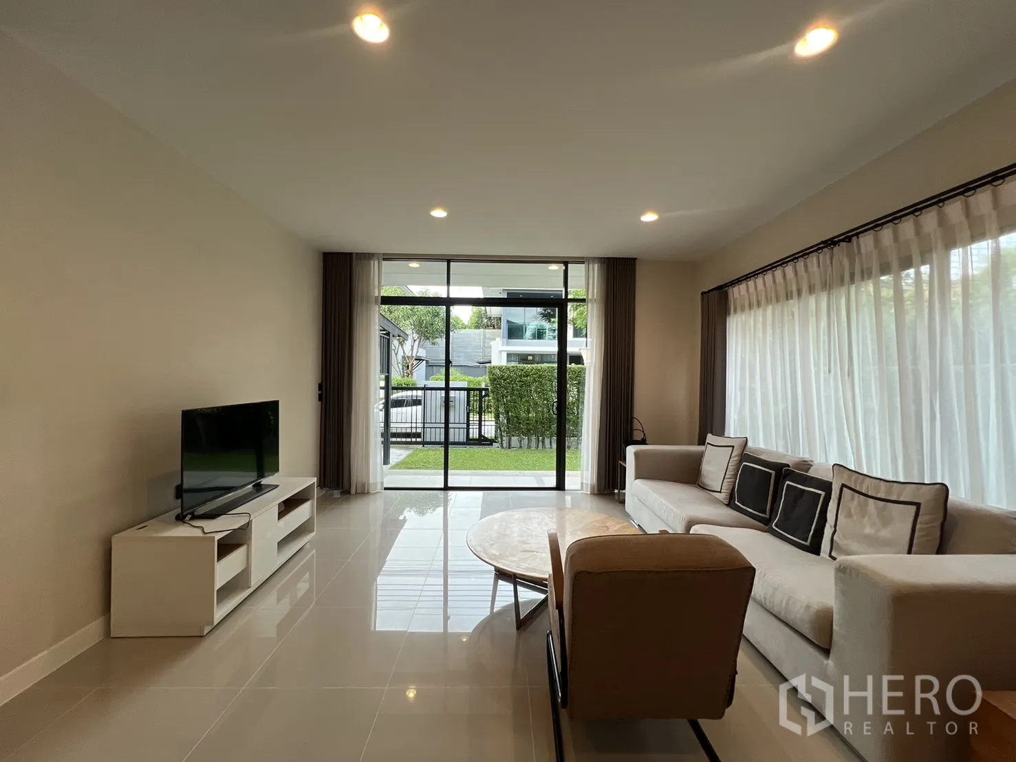 บ้าน ให้เช่าในBang Kapi, Bangkok - ห้องรับแขกสว่าง มองเห็นสวน มีชั้นวางทีวีและโซฟา