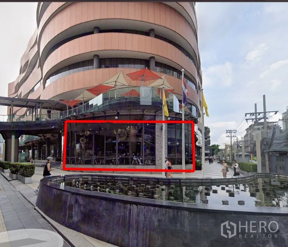 零售空间 for rent in Khlong Toei, Bangkok - 现代弧形建筑前的临街铺面，落地玻璃门面，旁有步行广场与水景喷泉。