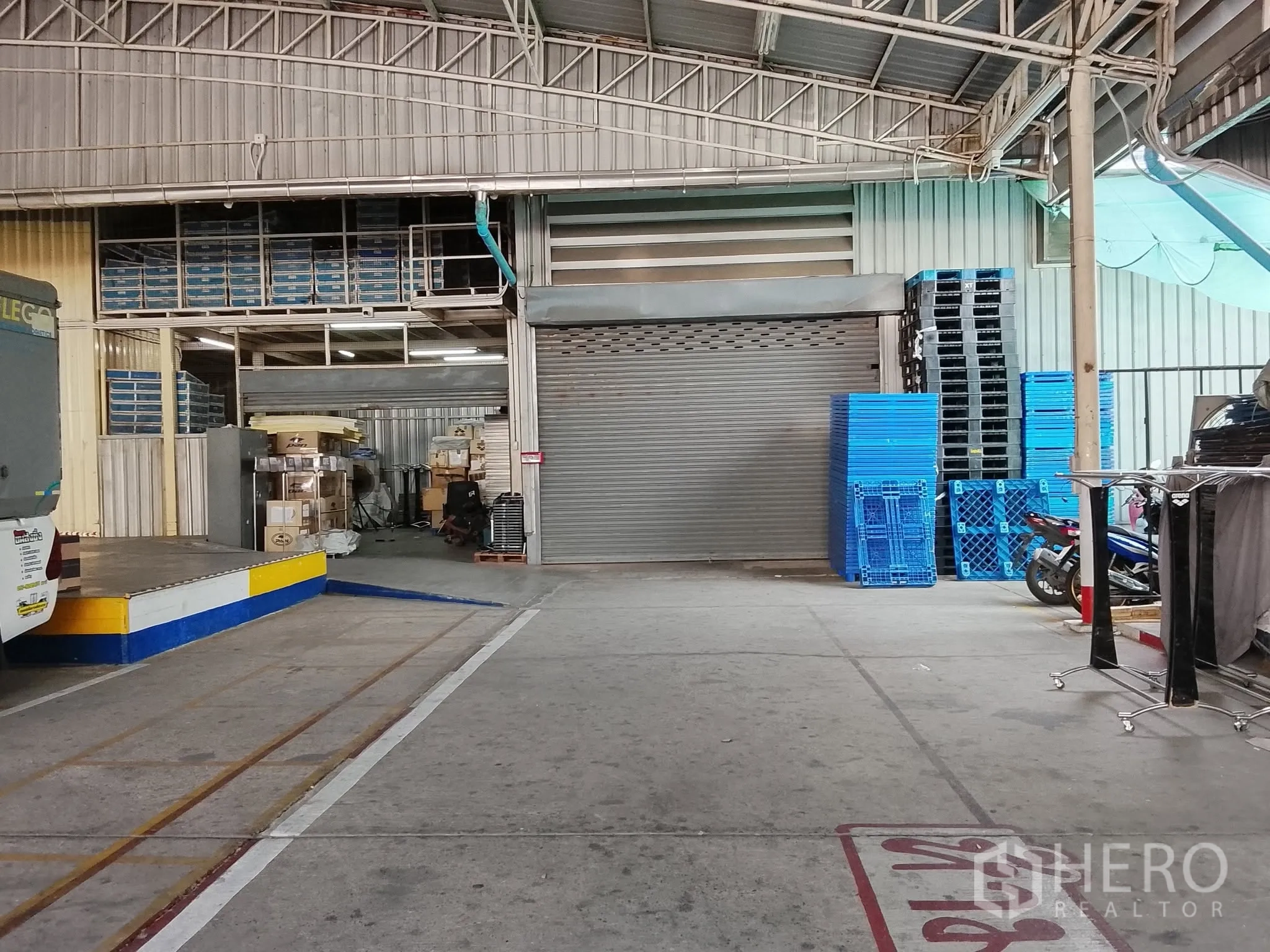 Warehouse for rent in Bang Kho Laem, Bangkok - Covered loading area outside the unit with roller door and stacked pallets.