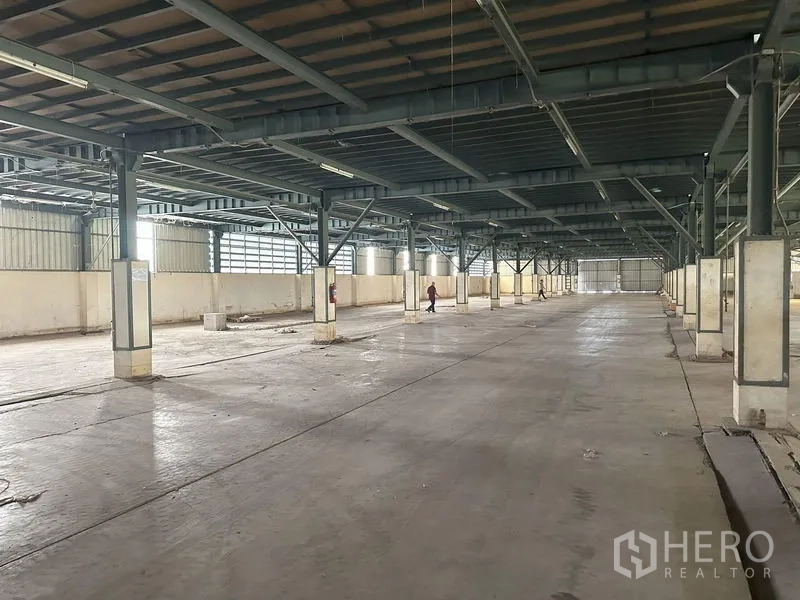 Factory for rent in Pathum Thani - Expansive warehouse hall with steel columns and a wide central aisle.