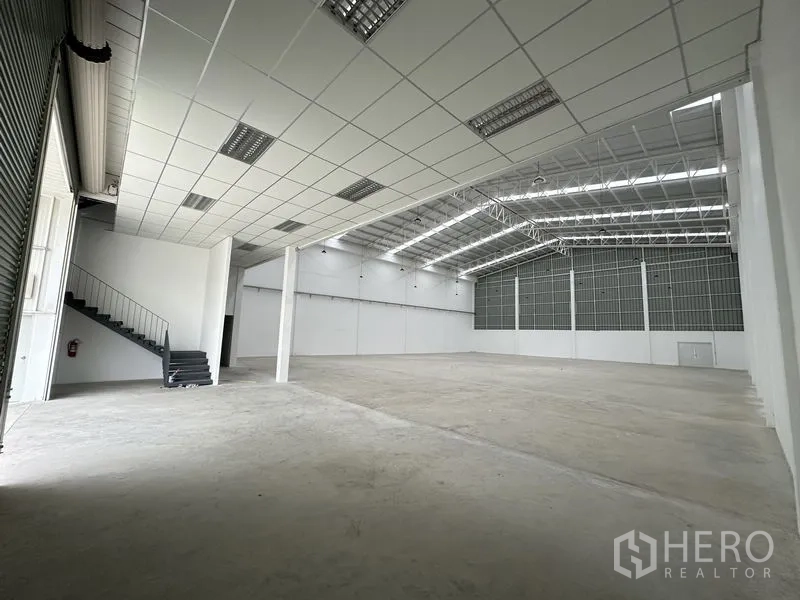 โรงงาน ให้เช่าในPathum Thani - ภายในโกดังพร้อมโครงหลังคาเหล็ก บันไดขึ้นชั้นลอย และประตูโหลดสินค้า