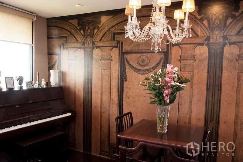 Condominium for rent in Watthana, Bangkok - Dining nook with crystal chandelier, small wooden table, upright piano and classical column wallpaper.