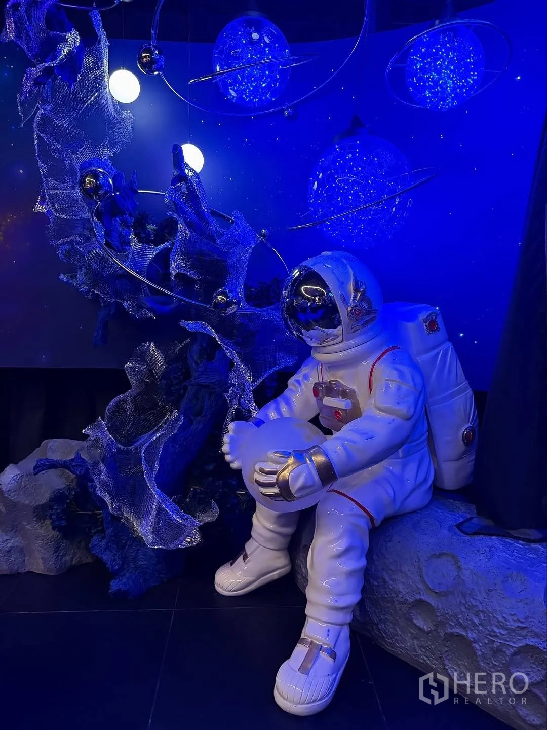 Retail Space for rent in Watthana, Bangkok - Astronaut statue set against deep-blue cosmic backdrop with glowing planets.