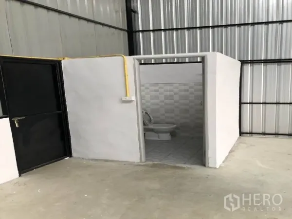 คลังสินค้า ให้เช่าในPathum Thani - ห้องน้ำภายในโกดัง ผนังปูกระเบื้อง ข้างประตูเหล็กสีดำและท่อสาธารณูปโภคสีเหลือง