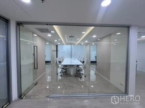 办公空间 出租在Din Daeng, Bangkok - 玻璃隔断会议室，长条白色会议桌，大理石地面与LED照明，可见城市景观。