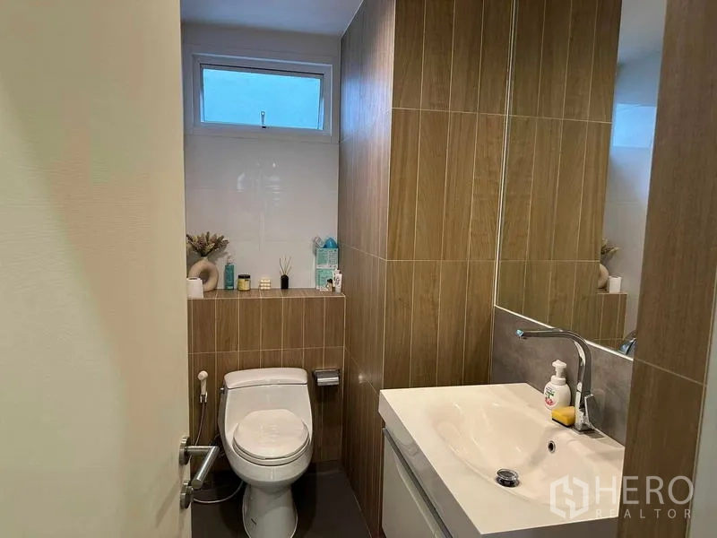 Detached House for sale in Suan Luang, Bangkok - Guest bathroom with wood-grain tiles, vanity and a small window.