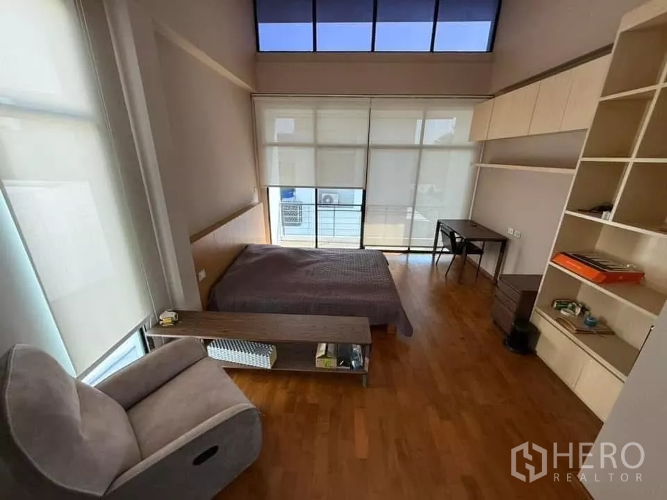 Detached House for rent or sale in Bueng Kum, Bangkok - Spacious bedroom with balcony glazing, built-in shelves, desk, recliner and roller blinds.