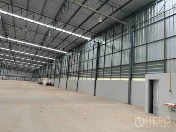 Warehouse for rent in Lat Krabang, Bangkok - Side wall of the warehouse featuring ventilation louvers, a service door, and ceiling-hung lights.