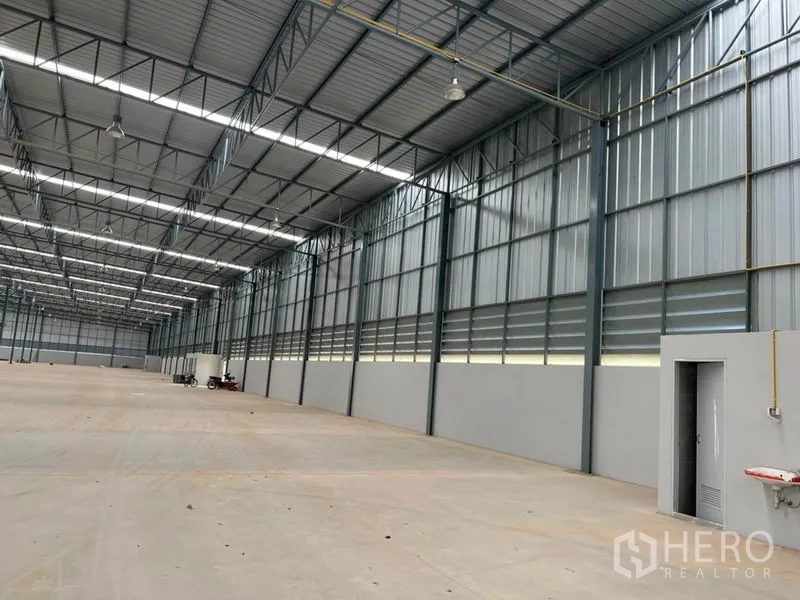 Warehouse for rent in Lat Krabang, Bangkok - Side wall of the warehouse featuring ventilation louvers, a service door, and ceiling-hung lights.