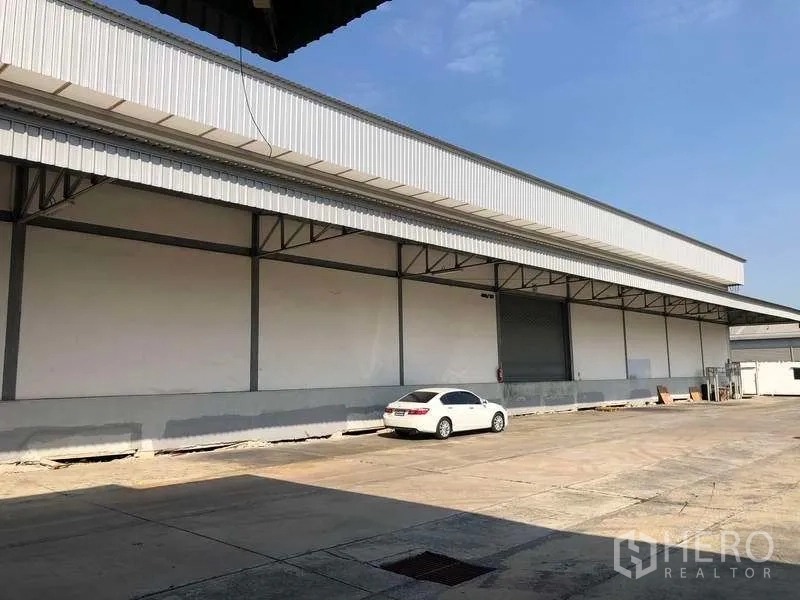 คลังสินค้า ให้เช่าในBang Phli, Samut Prakan - ด้านหน้าโกดังยาว มีประตูม้วนและถนนกว้างสำหรับการสัญจร