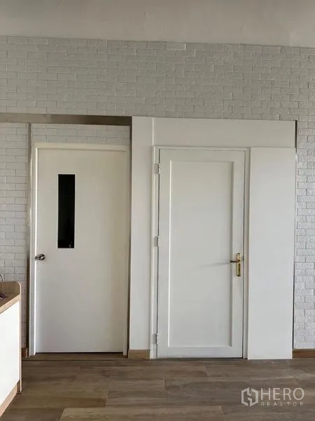 零售空间 出租 - 白砖墙前的服务区门与下方收纳柜体。