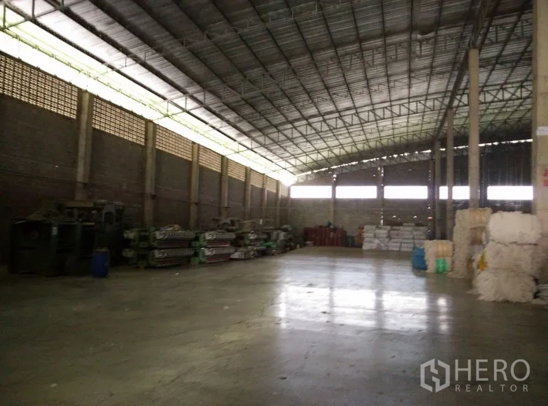 Factory for rent or sale in Krathum Baen, Samut Sakhon - Large open production hall with high clear-span roof, ventilation and organized storage on a concrete floor.