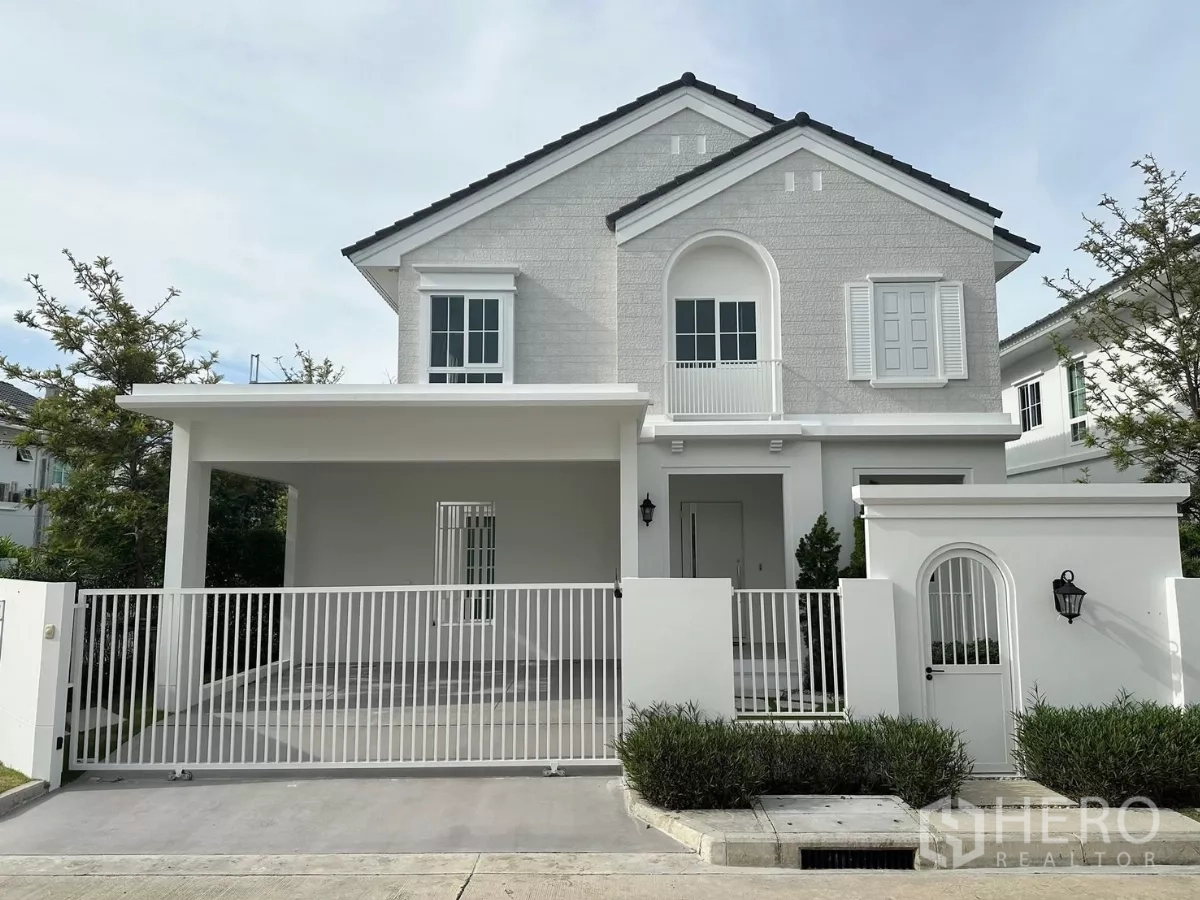 独立式住宅 出租在Bang Phli, Samut Prakan - 转角位置的两层独栋住宅，白色外立面，带入户车库与围栏。