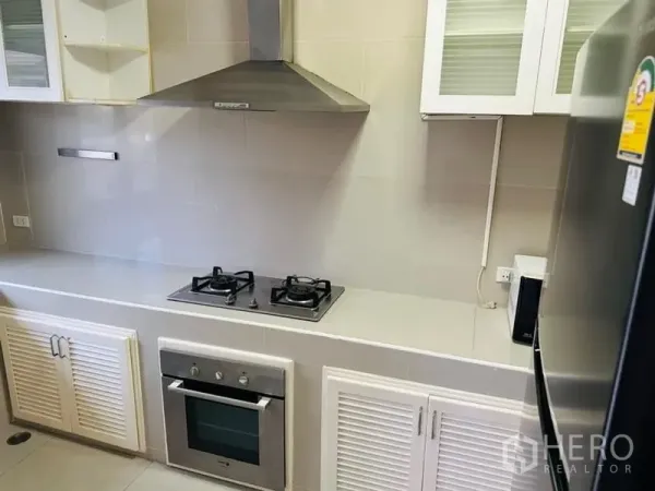 Home Office for rent in Watthana, Bangkok - Modern kitchen with gas hob, built-in oven, range hood, and white cabinetry.