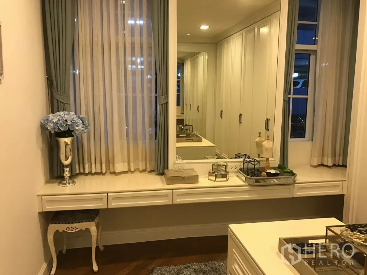 Townhouse for sale in Watthana, Bangkok - Bright dressing area with vanity, large mirror and floor-to-ceiling wardrobes.