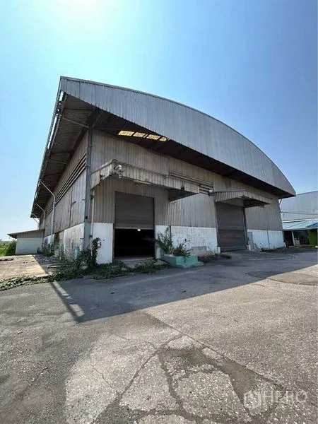 Warehouse for rent in Sam Phran, Nakhon Pathom - Warehouse exterior with loading bays and multiple roller shutter doors beneath a metal canopy.
