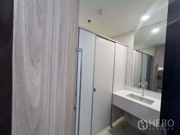 办公空间 出租在Din Daeng, Bangkok - 翻新卫生间，白色洗手台与大镜面，独立隔间配大理石纹饰面。