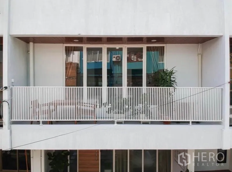 ทาวน์เฮาส์ ให้เช่าในKhlong Toei, Bangkok - ระเบียงหน้าบ้านราวเหล็กสีขาวและประตูกระจกบานเลื่อนของทาวน์เฮาส์ร่วมสมัย