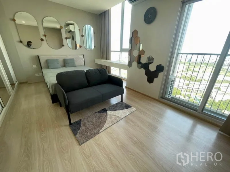 Condominium for rent in Huai Khwang, Bangkok - Master bedroom with bed, loveseat, decorative wall art and two balcony doors.