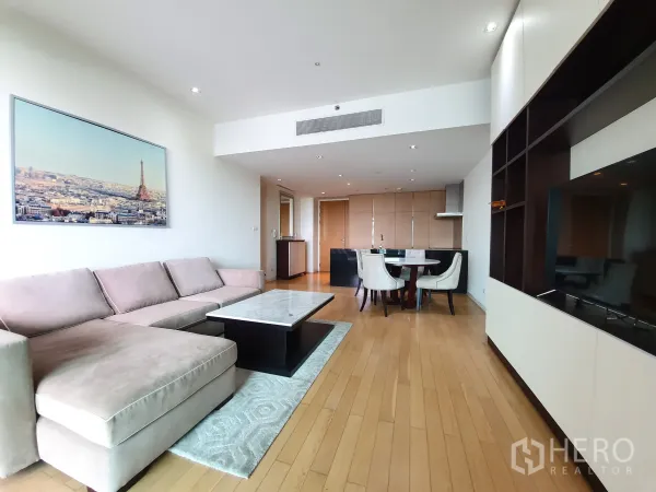 Condominium for rent or sale in Yan Nawa, Bangkok - Open‑plan living and dining area with L‑shaped sofa, TV wall, and kitchen in the background.
