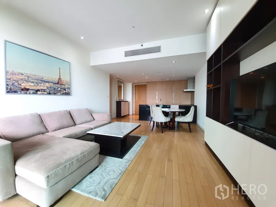 Condominium for rent or sale in Yan Nawa, Bangkok - Open‑plan living and dining area with L‑shaped sofa, TV wall, and kitchen in the background.