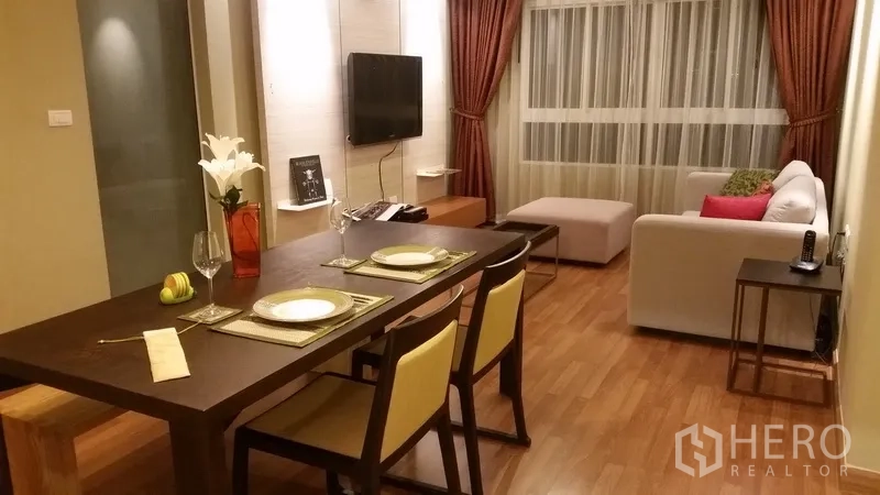 คอนโด ให้เช่าในKhlong San, Bangkok - ห้องนั่งเล่นและรับประทานอาหารแบบเปิด พื้นไม้ โซฟา ผนังทีวี และหน้าต่างผ้าม่านขนาดใหญ่