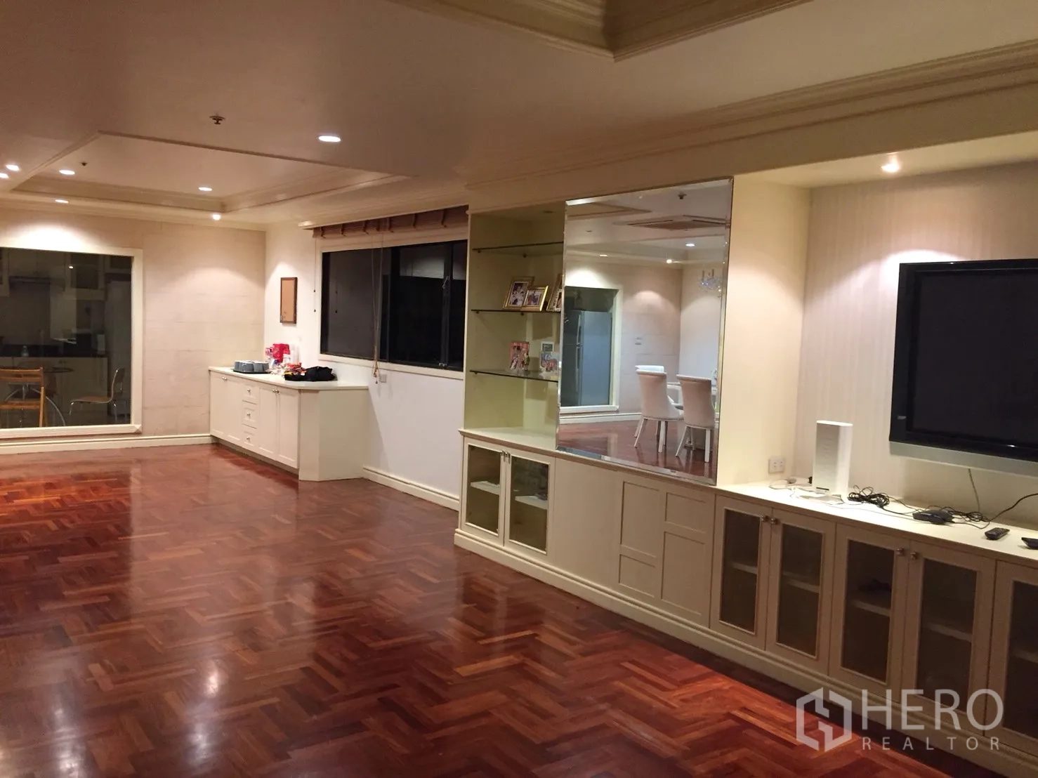 Condominium for rent in Watthana, Bangkok - Large living room with built-in TV cabinet and shelving, polished parquet floors, and window.
