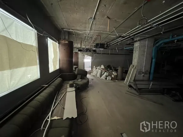 พื้นที่ขายปลีก ให้เช่าในKhlong Toei, Bangkok - พื้นที่มืดมีโซฟายาวบิลท์อินและวัสดุก่อสร้างกองอยู่