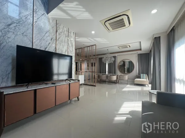 บ้าน ให้เช่าหรือขายในPrawet, Bangkok - โถงรับแขกกว้างเชื่อมพื้นที่ทานอาหาร ทีวีจอใหญ่ ผนังหินอ่อน และไฟฝ้าซ่อนไฟ