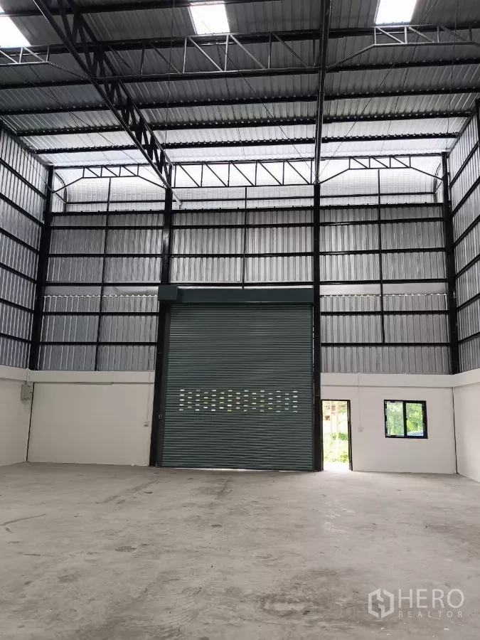 คลังสินค้า ให้เช่าในBang Phli, Samut Prakan - พื้นโกดังโล่งหันสู่ประตูม้วนขนาดใหญ่ มีประตูเข้าด้านข้างรับแสงธรรมชาติ