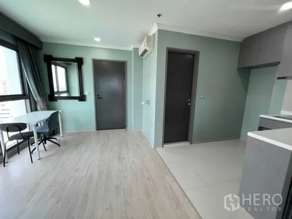 Condominium for sale in Ratchathewi, Bangkok - Open-plan space linking living area to kitchenette with abundant natural light from corner windows.