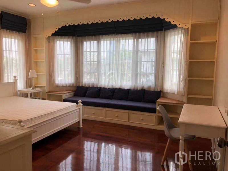 独立式住宅 出租在Bang Na, Bangkok - 家庭卧室，飘窗坐榻、开放书架、书桌与白色床。