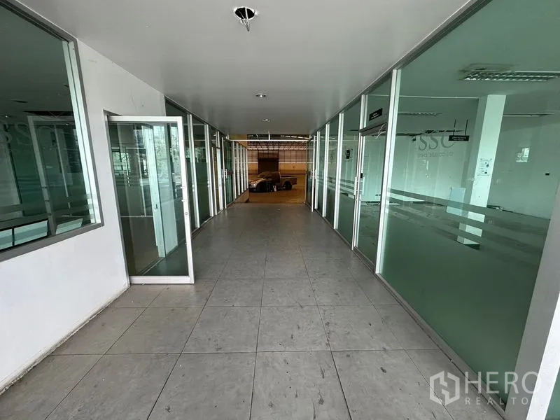 Showroom for rent or sale in Lam Luk Ka, Pathum Thani - Hallway lined with glass-partitioned offices and open doors.
