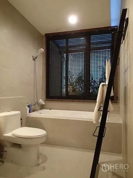 Townhouse for rent in Watthana, Bangkok - Modern bathroom with bathtub, shower, toilet, and large window with blinds.