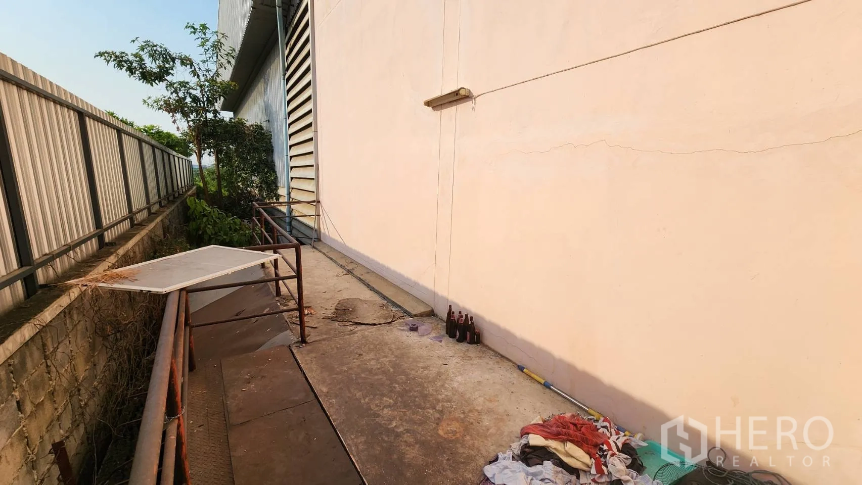 货栈 出租在Nonthaburi - 侧院混凝土通道，靠墙摆放维护物品。