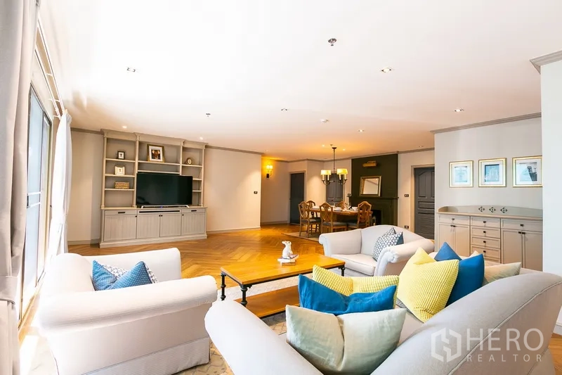 房间 出租在Khlong Toei, Bangkok - 通透客厅，沙发与彩色抱枕，内置电视墙柜。