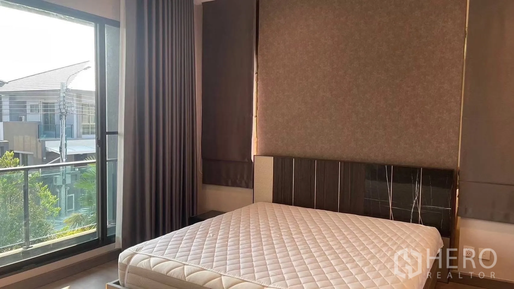 Detached House for rent in Prawet, Bangkok - Bright bedroom with large bed, floor-to-ceiling window and balcony view.