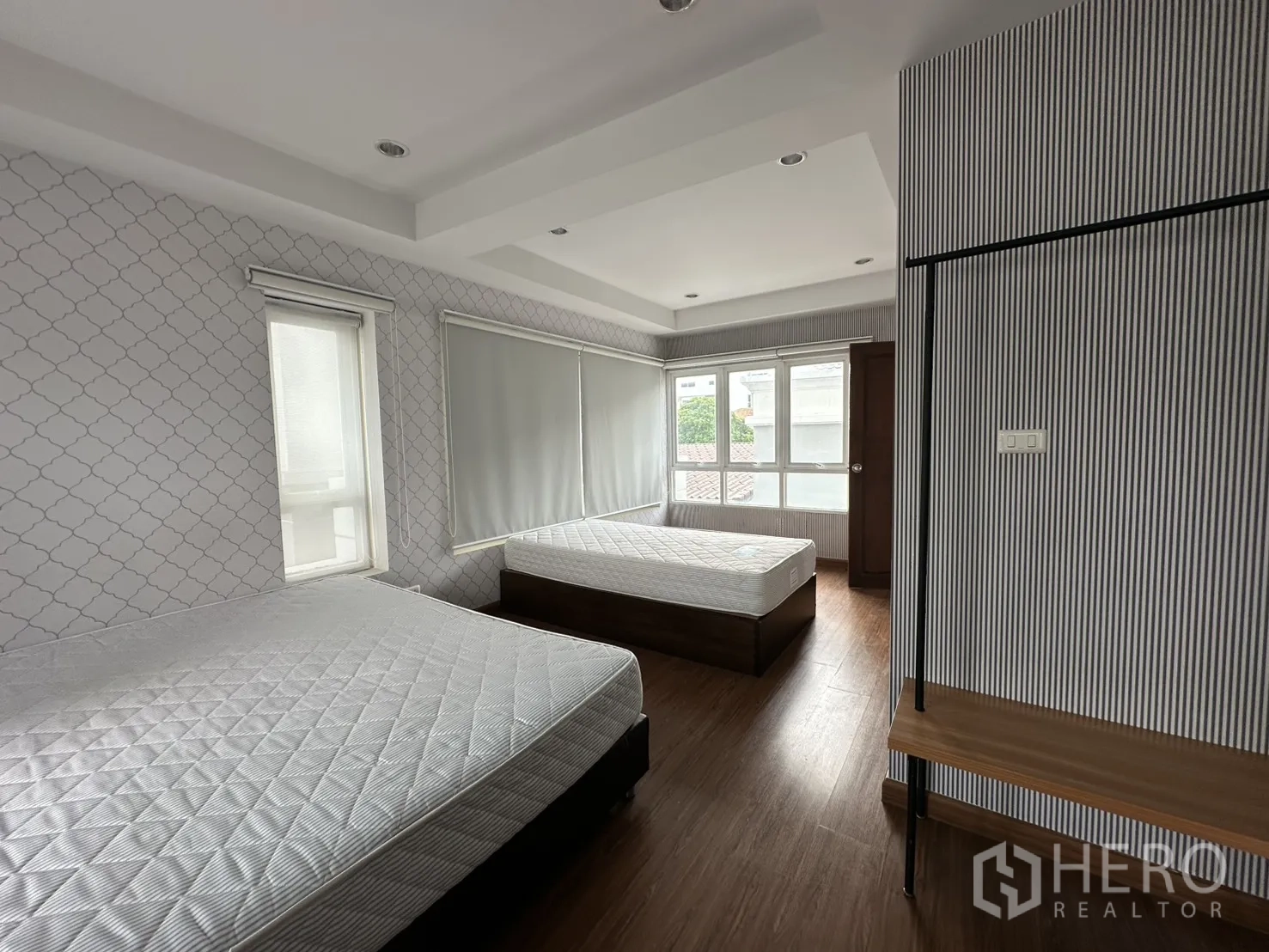 Home Office for rent in Watthana, Bangkok - Twin-bed bedroom from another angle showing large corner windows and blinds.