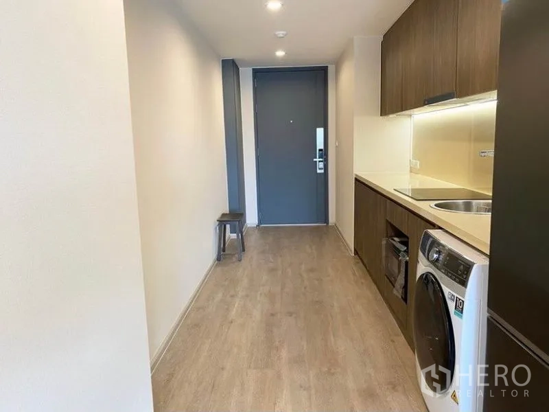 Condominium for rent in Pathum Wan, Bangkok - Entrance hallway with built-in kitchenette and laundry, wood flooring and recessed lighting.