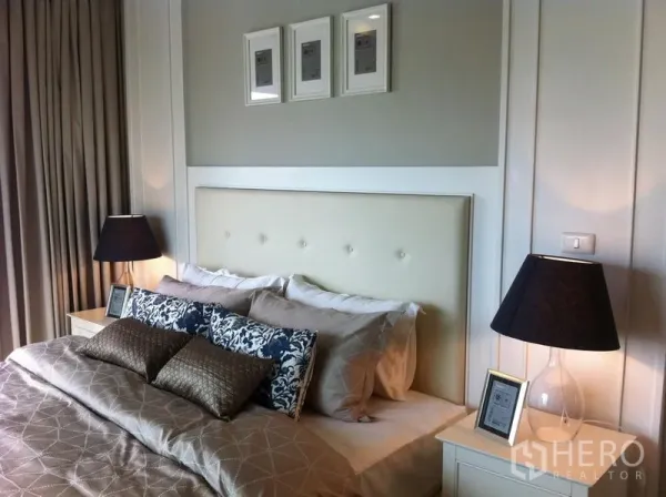 คอนโด ให้เช่าในBangkok - ภาพระยะใกล้เตียงนอน หัวเตียงบุผ้า หมอนตกแต่ง และโคมไฟข้างเตียง