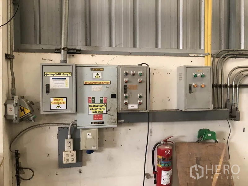 Factory for sale in Khlong Luang, Pathum Thani - Industrial electrical control panels and fire extinguisher inside the factory.